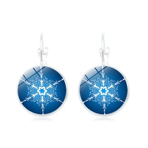 Macro view of round glass earrings with blue gradient and white snowflake pattern detail