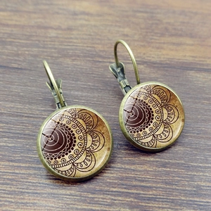 Macro view of vintage bronze earrings with brown bohemian mandala patterns on wood