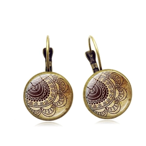 Close-up of vintage bronze mandala earrings with geometric patterns and glass dome