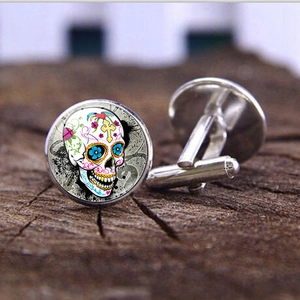 Primer plano de gemelos plateados con diseño de calavera mexicana colorida sobre madera