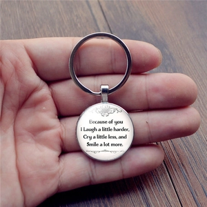 Because of You silver metal keychain with glass gem letter pendant on wood surface