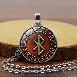 Macro detail of Viking Rune pendant with glass dome and bronze chain on wooden background