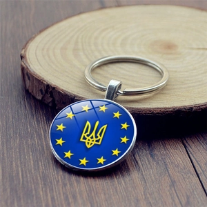 Detailed macro view of Ukraine emblem and EU stars charm on a round silver keychain