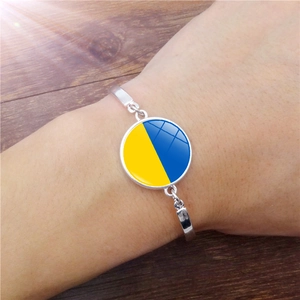 Detail van zilveren armband met Oekraïense vlag glazen hanger gedragen om de pols