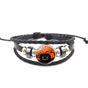 Detail of multi-layered Halloween leather bracelet with orange pumpkin glass cabochon