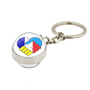 Gros plan du porte-clés en métal argenté avec pendentif en verre, poignée de main et cœur