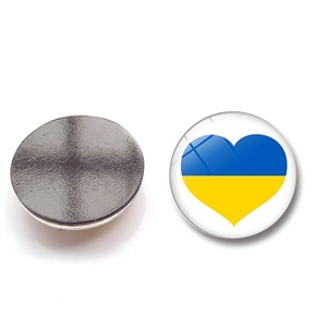 Close-up of circular fridge magnet with blue and yellow heart and textured magnetic back