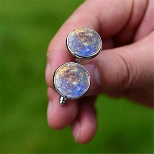 Detailed close-up of galaxy-themed shirt cufflinks featuring intricate nebula planet patterns