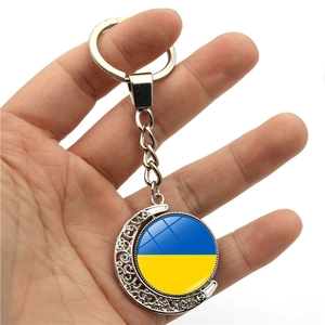 Rotating Ukraine flag moon keychain with silver metallic frame held against white background