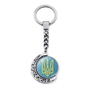Detail of silver rotating moon keychain with blue Ukraine trident symbol on white backdrop