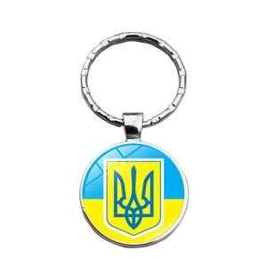 Detail of silver round keychain with Ukraine flag and coat of arms under glass dome
