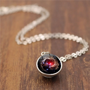 Cosmic galaxy nebula double-sided glass ball pendant necklace on brown wooden background