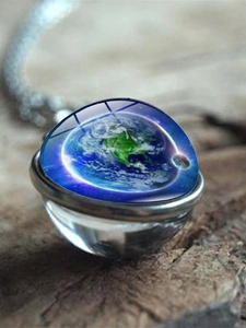 Close-up of double-sided glass planet pendant with Earth motif on rustic wood
