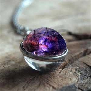 Cosmic galaxy planet double-sided glass ball pendant necklace on a rustic wood background
