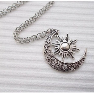 Macro view of vintage silver sun and moon pendant with filigree details on a chain