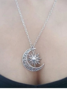 Close-up of vintage silver crescent moon and sun pendant necklace on model's neck
