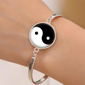Detailed view of silver Tai Chi Yin Yang charm bracelet with glass cabochon on wrist