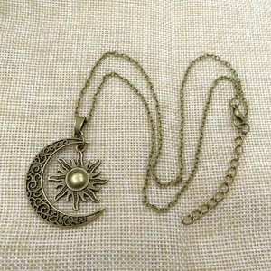 Vintage bohemian celestial necklace with antique bronze sun and moon pendant on burlap