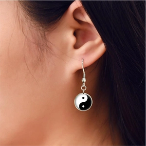 Close-up of model wearing silver Yin Yang Tai Chi earrings with glass gem inlay