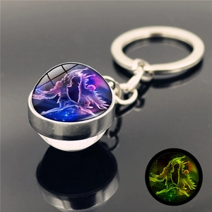 Luminous double-sided glass orb keychain with celestial design showing green glow effect