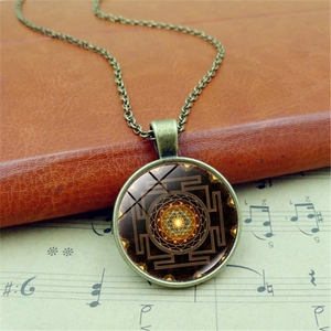 Vintage Sri Yantra mandala pendant necklace with bronze chain on a retro background