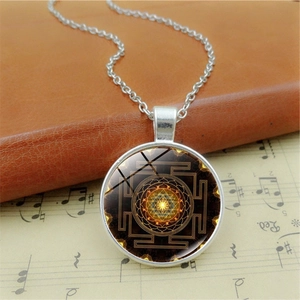 Detailed close-up of a Yantra glass gem pendant necklace with mandala pattern on vintage music paper