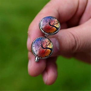 Detailed close-up of a silver Tree of Life cufflink with colorful artistic background