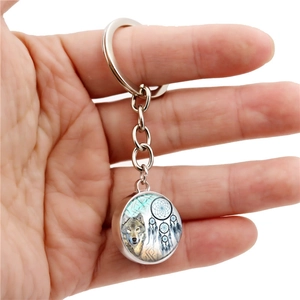 Detailed view of wolf and dreamcatcher glass pendant on silver keychain held in hand
