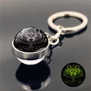 Luminous wolf head glass ball keychain with a glowing green effect in the dark
