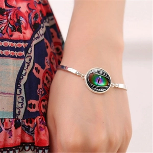 Detail of silver chain bracelet featuring a realistic colorful dragon eye glass pendant