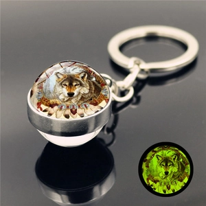 Detailed view of the luminous glass ball keychain showing the wolf pattern in the dark