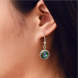 Detail of silver drop earrings with glowing purple and green dragon eye glass domes