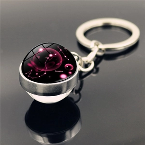 Macro shot of Scorpio zodiac glass dome pendant on metal keychain over dark mirror surface