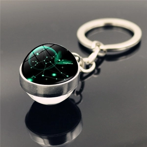 Close-up of Sagittarius constellation glass sphere keychain on a black reflective surface