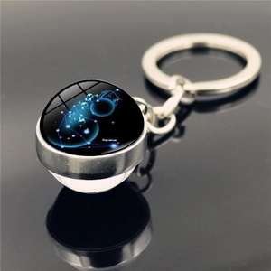 Aquarius zodiac crystal ball keychain with silver metal ring on reflective black surface