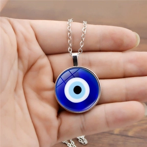 Κοντινό πλάνο ενός μπλε μενταγιόν Evil Eye από γυαλί στο χέρι με ασημένια αλυσίδα