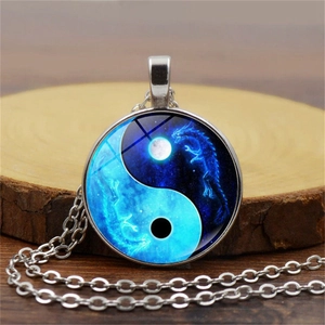 Yin Yang Tai Chi glass pendant necklace with blue dragon pattern on wooden base