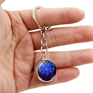 Close-up of Aries constellation glass ball keychain with glowing blue metal pendant