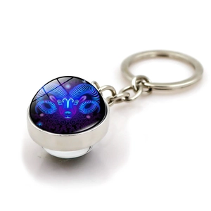 Detail of silver zodiac keychain with glass dome showing neon Aries constellation symbol
