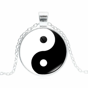 Detail of Yin Yang Tai Chi pendant necklace with polished silver chain on white background
