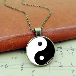 Vintage bronze Yin Yang pendant necklace displayed on antique music sheet and book