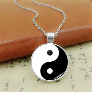 Vintage Yin Yang Tai Chi glass pendant necklace with silver chain on retro music sheet