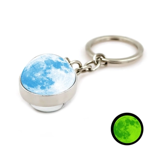 Détail macro du porte-clés lune avec boule de verre et effet lumineux vert nocturne