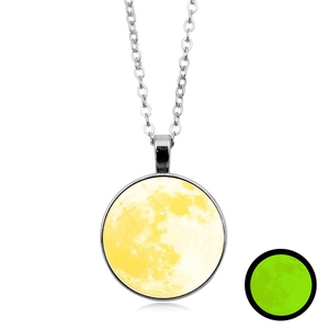 Detalle del collar con colgante de luna luminosa con efecto de brillo verde en la noche