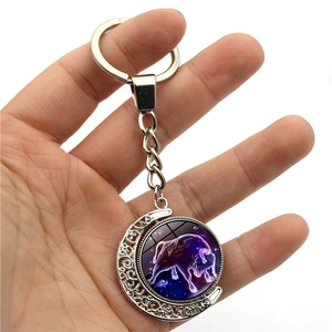 Glow-in-the-dark Taurus zodiac keychain with rotating silver metal crescent moon pendant