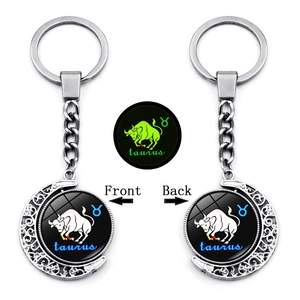 Close-up of rotating Taurus zodiac keychain with luminous moon pendant and silver finish