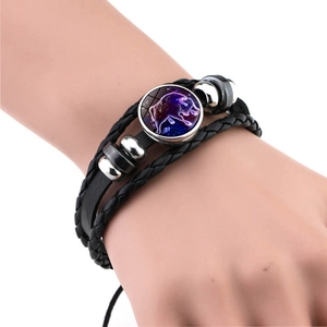 Gros plan d'un bracelet multicouche en cuir noir avec pendentif lumineux du zodiaque Taureau