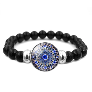 Dettaglio macro delle perle nere da 8mm e del ciondolo occhio blu sul bracciale