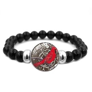 Detail of beaded bracelet with cardinal glass cabochon and polished black beads