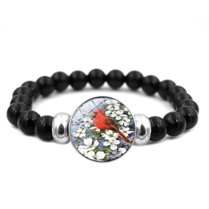 Detail of beaded bracelet with black polished stones and cardinal bird glass charm